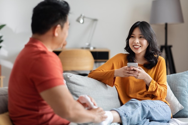 Marito asiatico amorevole che massaggia i piedi della moglie sorridente