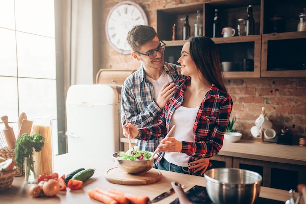 Marito che bacia la moglie in cucina mentre lei cucina