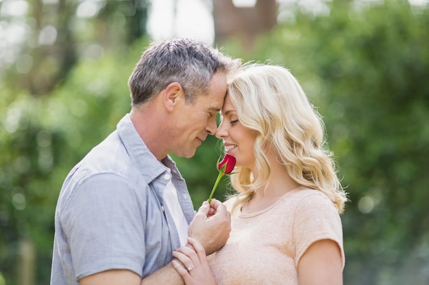 Marito che offre una rosa alla moglie fuori nella foresta