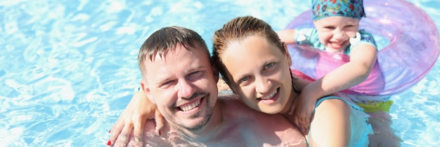 Marito con moglie e figlio nuotano insieme in piscina