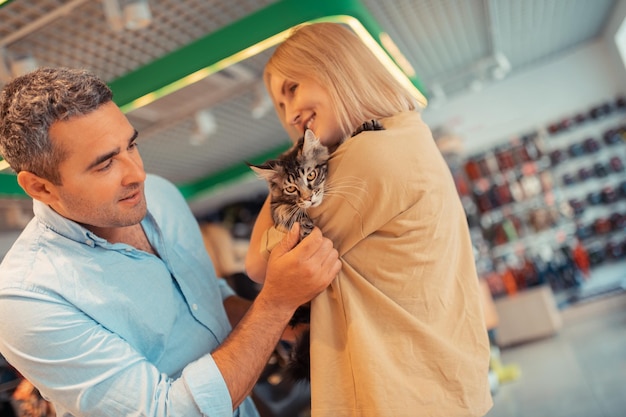 Marito dai capelli grigi che sorride mentre guarda la moglie che tiene il gatto