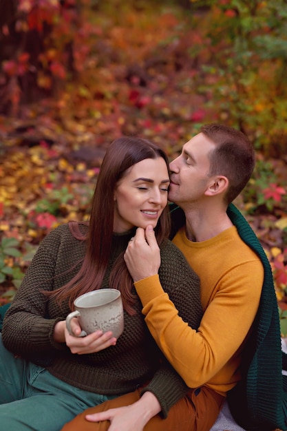 Marito e moglie si abbracciano per un picnic autunnale con zucca, mele, tè