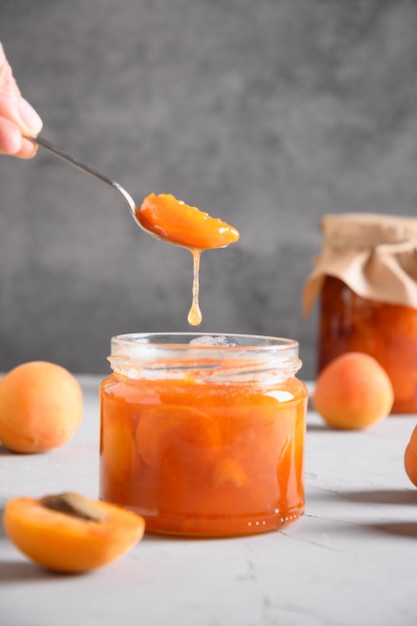 Marmellata di albicocche fatta in casa in cucchiaio in mano di donna