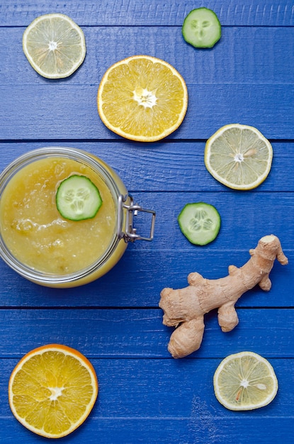 Marmellata di cetrioli in un barattolo di vetro con fette di limone e cetriolo ingredienti arancione su un tavolo di legno blu. orientamento verticale. concetto di mangia sano.