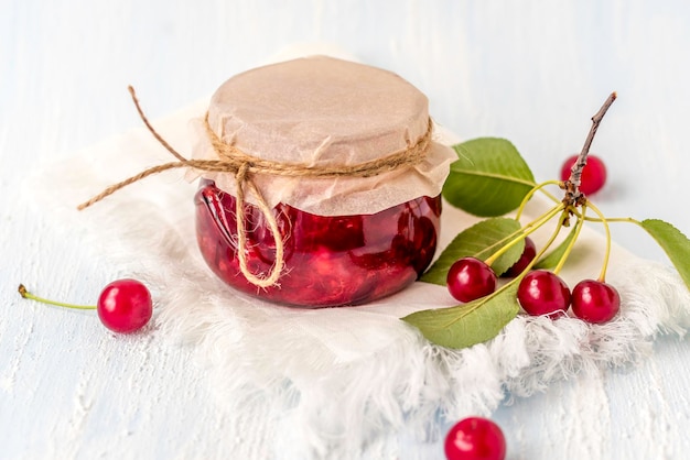 Marmellata di ciliegie con ciliegie fresche su fondo bianco