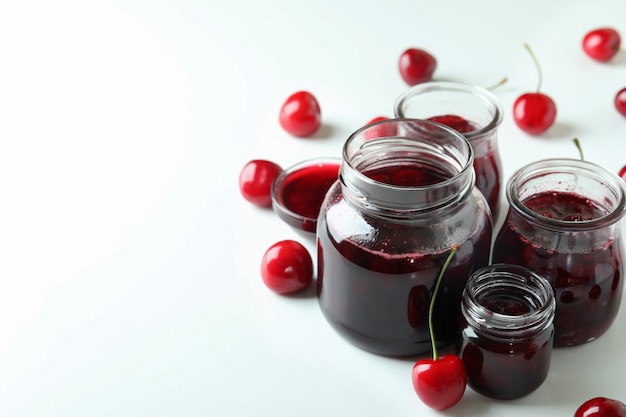 Marmellata di ciliegie e ingredienti su sfondo bianco