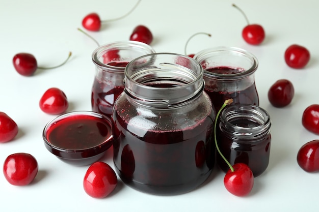 Marmellata di ciliegie e ingredienti su sfondo bianco