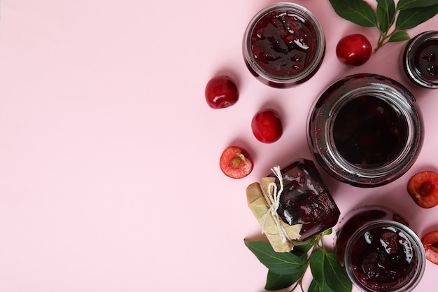 Marmellata di ciliegie e ingredienti su sfondo rosa