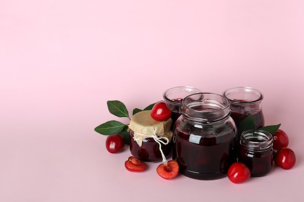 Marmellata di ciliegie e ingredienti su sfondo rosa