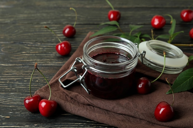 Marmellata di ciliegie e ingredienti su tavola in legno rustico