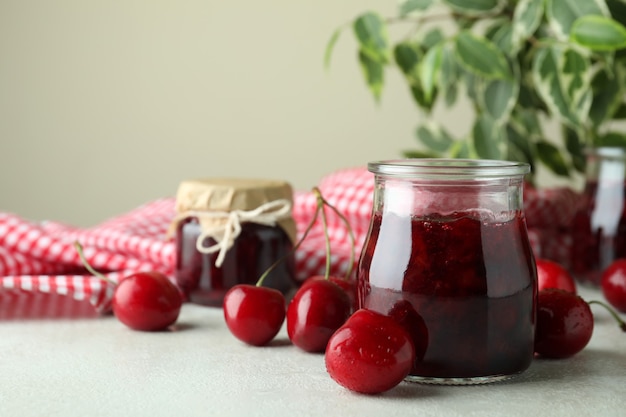 Marmellata di ciliegie e ingredienti sul tavolo bianco strutturato