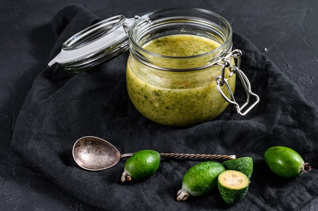 Marmellata di feijoa verde su un tagliere di legno in un barattolo di vetro.