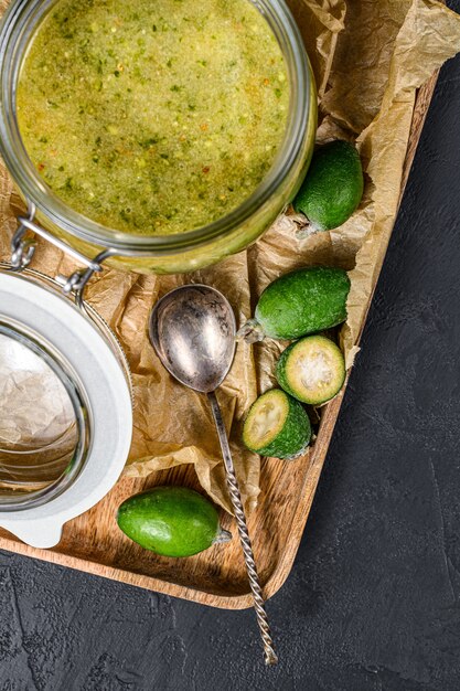 Marmellata di feijoa verde su un tagliere di legno in un barattolo di vetro.