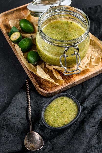 Marmellata di feijoa verde su un tagliere di legno in un barattolo di vetro.