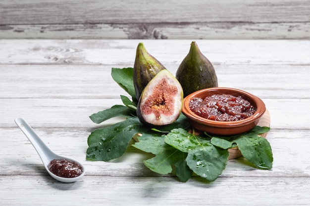 Marmellata di fichi con fichi, foglie di fico e cucchiaio bianco con marmellata