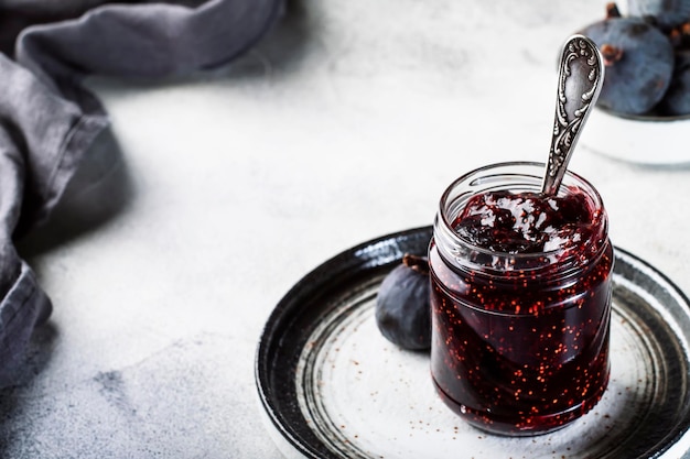 Marmellata di fichi in barattolo di vetro con fichi blu freschi Preparazioni fatte in casa e conserve Spazio per la copia di sfondo grigio