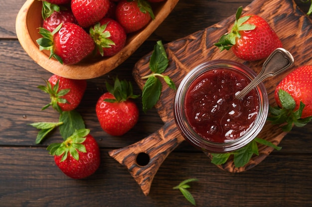 Marmellata di fragole Marmellata di fragole in vasetto di vetro con frutti di bosco freschi piatto su un vecchio tavolo in legno scuro sfondo primo piano Marmellata di fragole fatta in casa fruttata Vista dall'alto con spazio per la copia