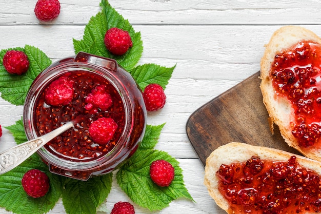 Marmellata di lamponi e panini con lampone fresco sul tavolo di legno bianco