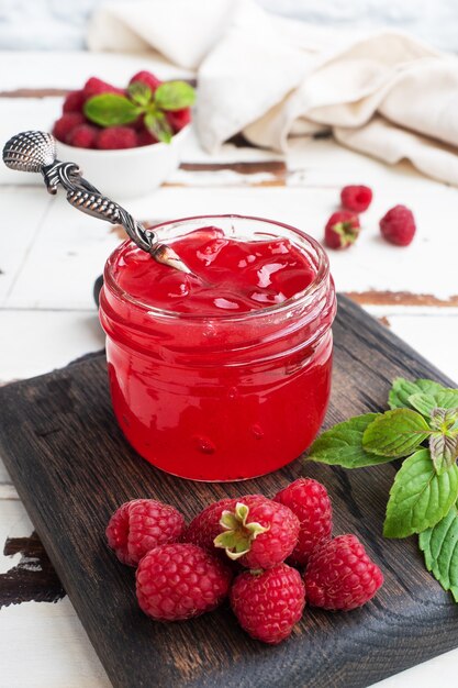 Marmellata di lamponi fatta in casa in un barattolo di vetro e lamponi freschi alla menta