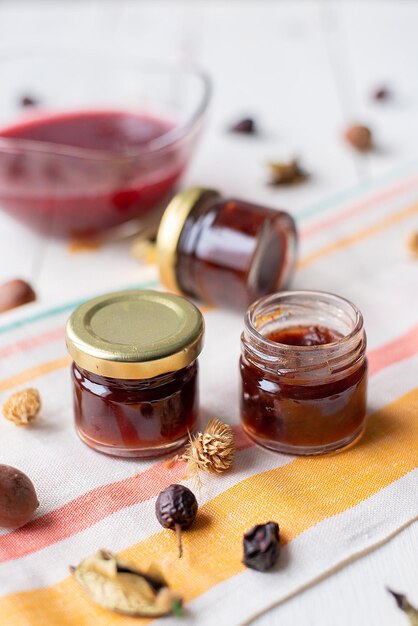 Marmellata di lamponi sul tavolo un vasetto con marmellata rossa su un tessuto chiaro arredamento rustico a base di foglie secche e noci cibo salutarexA