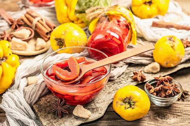 Marmellata di mele cotogne o confettura preparata con zucchero di canna. Frutti interi maturi, dolce da dessert, spezie fragranti. Supporto in legno alla moda, sfondo di vecchie tavole, primo piano