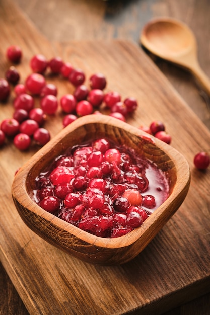 Marmellata di mirtilli rossi in una ciotola di legno su un fondo di legno.