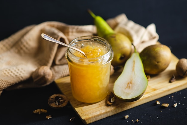 Marmellata di pere fatta in casa su una tavola di legno su uno sfondo nero