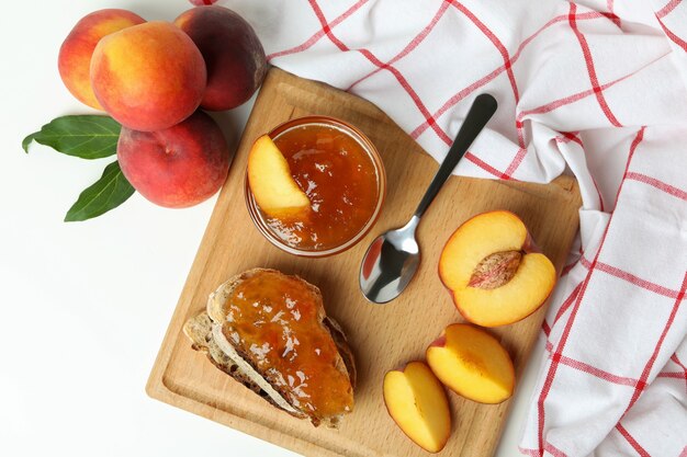 Marmellata di pesche, panino con marmellata di pesche e ingredienti su sfondo bianco