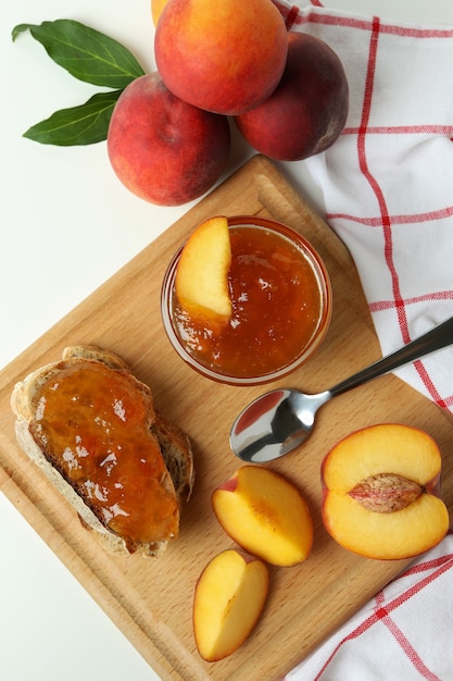 Marmellata di pesche, panino con marmellata di pesche e ingredienti su sfondo bianco