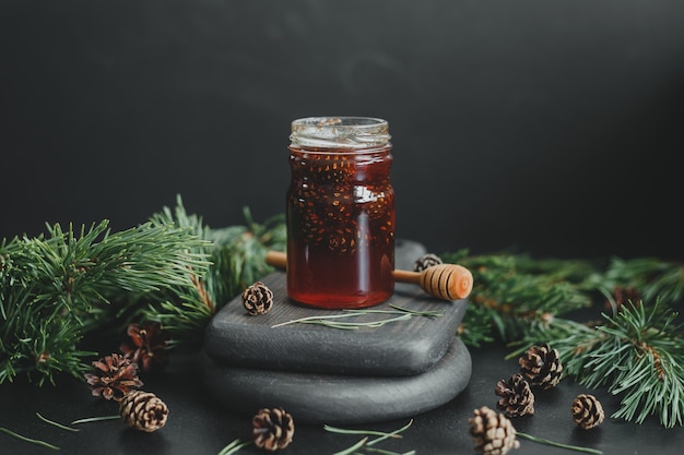 Marmellata di pigne in un barattolo di vetro sullo sfondo di rami e pigne di pino