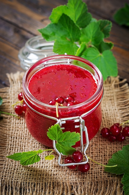 Marmellata di ribes in un barattolo su una superficie di legno. Cibo gustoso.