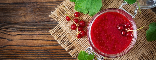 Marmellata di ribes in un barattolo su una superficie di legno.