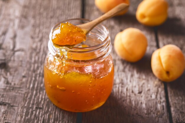 Marmellata fatta in casa di albicocche in un barattolo di vetro su uno sfondo di legno Gustoso dessert orizzontale