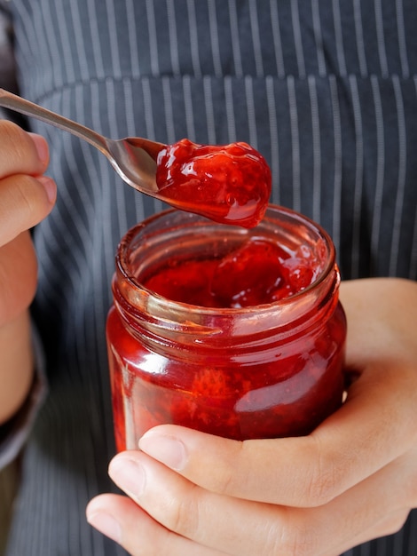 Marmellata rossa fragola e pesca gialla su tavola di legno e fetta di pane.