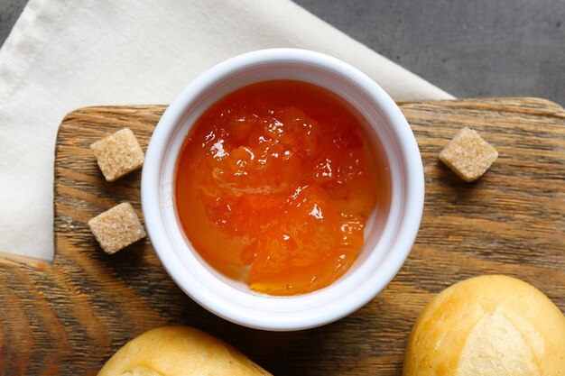 Marmellata saporita nel barattolo e ciotola cracker e panini freschi primo piano