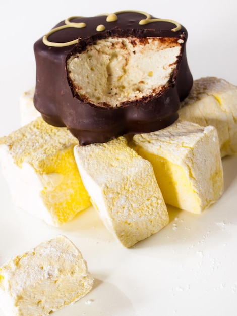 Marshmallow gourmet al frutto della passione ricoperti di cioccolato su sfondo bianco.