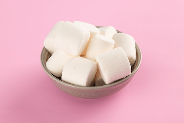 Marshmallow in ciotola su sfondo rosa pastello.