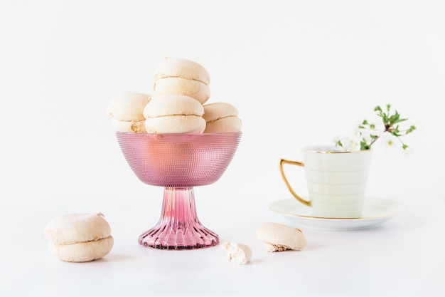 Marshmallow in un vaso.Tazza da tè con fiori.Superficie bianca.Minimalismo.