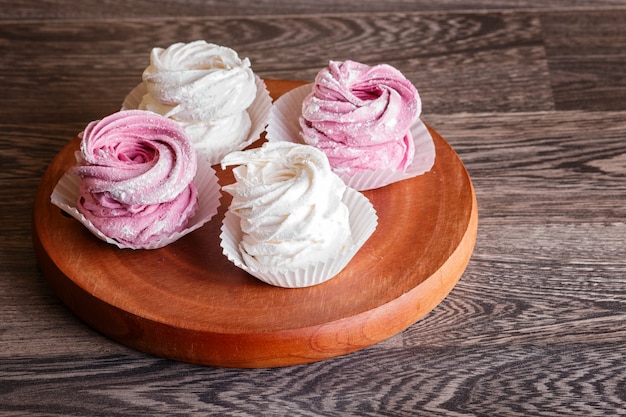 Marshmallow rosa e bianco su una tavola di legno rotonda