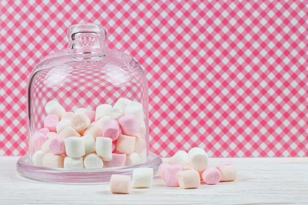 Marshmallow rosa in una campana di vetro su sfondo a scacchi rosso