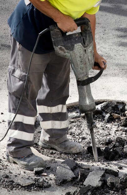 martello pneumatico nelle mani del disboscamento del lavoratore dell'asfalto