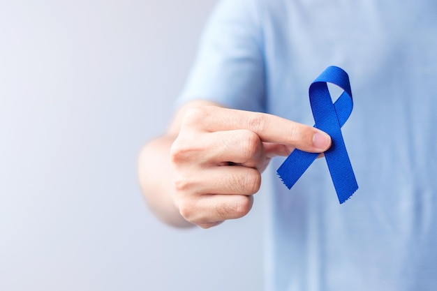 Marzo Mese della consapevolezza del cancro colorettale Donna che tiene un nastro blu scuro per sostenere le persone che vivono e le malattie Speranza sanitaria e concetto di giornata mondiale del cancro