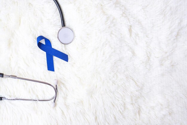 Marzo mese di consapevolezza del cancro colorettale, nastro blu scuro con stetoscopio su sfondo bianco per sostenere le persone che vivono e le malattie. Sanità, speranza e concetto di Giornata mondiale del cancro