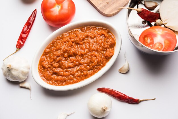 Masala o purea di pomodoro cipolla per salsa indiana, servita in una ciotola con tamatar crudo, pays e lehsun e peperoncino