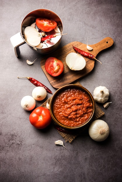 Masala o purea di pomodoro cipolla per salsa indiana, servita in una ciotola con tamatar crudo, pays e lehsun e peperoncino