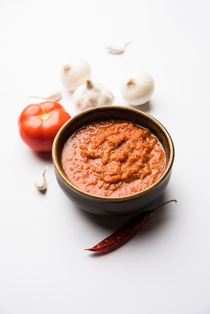 Masala o purea di pomodoro cipolla per salsa indiana, servita in una ciotola con tamatar crudo, pays e lehsun e peperoncino