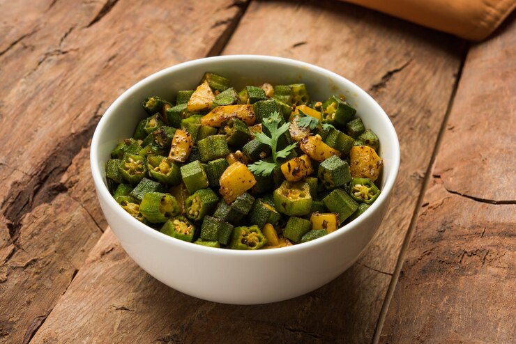 Photo masala sabji ala india atau sabzi dari bhindi goreng atau okra juga dikenal sebagai ladyfinger, disajikan dalam mangkuk dengan latar belakang suram. fokus selektif