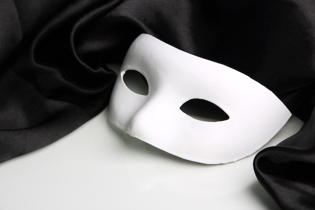 Maschera bianca e tessuto di seta nero isolato su bianco