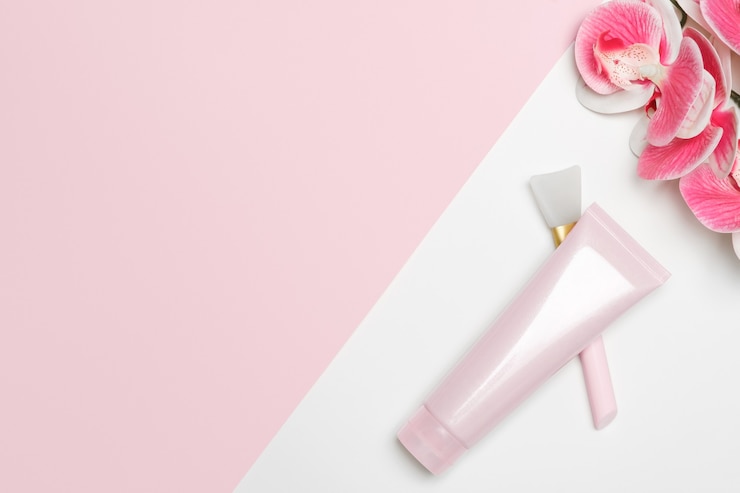 Foto maschera cosmetica per il viso su sfondo chiaro con un'orchidea. tubo e strumento di applicazione.