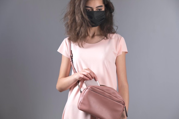 Maschera da donna e telefono sulla borsa